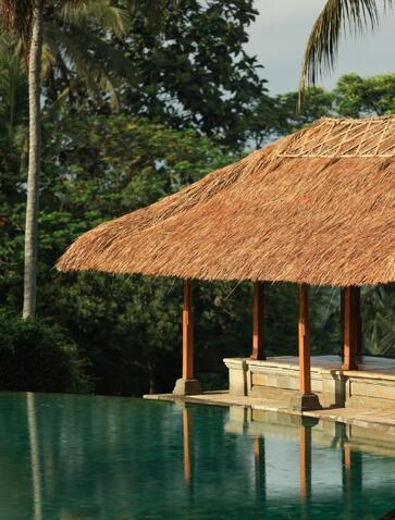 منزل الحمام بسقف من القش يطل على حمام السباحة في منتجع أمانداري بأوبود.