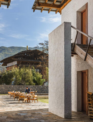 Outdoor dining area at Amankora's Bumthang Lodge, with wooden table and mountain views beyond.