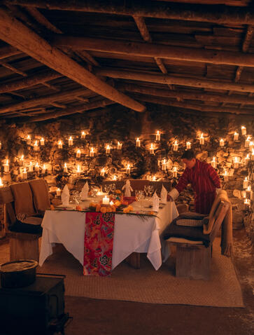 Candlelit dining room at Amankora's Gangtey Lodge with hanging lanterns and set tables for dinner.