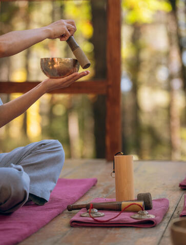 Sound bath therapy session at Amankora's Thimphu lodge, with hands forming heart shape above singing bowl.