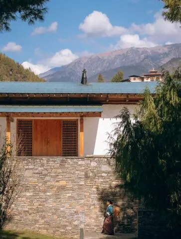 Stone villa with wooden door at Amankora, Paro, overlooking lake and mountain valley.