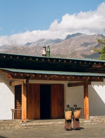 Traditional Bhutanese architecture at Amankora in Paro, with wooden doors and mountains beyond.