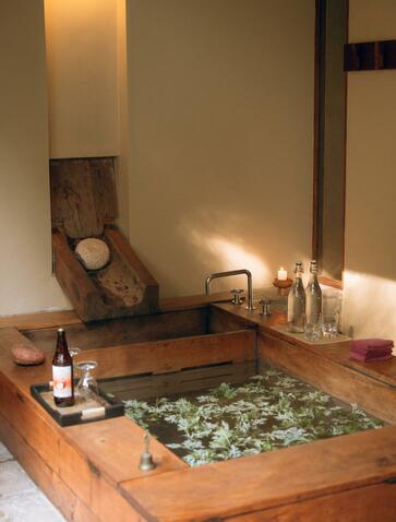 Hot stone bath at Amankora in Paro, Bhutan, with traditional wooden tub and warm lighting.