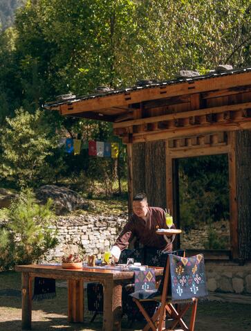 Guests enjoying a recovery lunch at Amankora's Paro Lodge log cabin surrounded by forest.