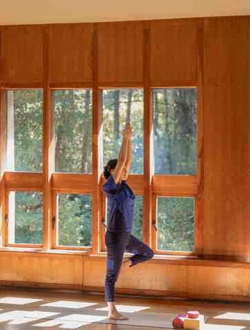 Woman practising yoga by wooden-framed windows at Amankora's Paro Lodge.