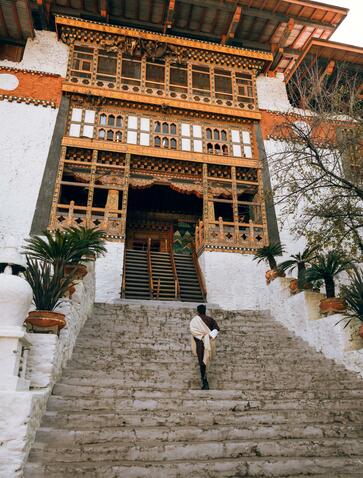 Wooden architectural detail on a whitewashed building at Amankora in Punakha, Bhutan, with stone steps leading to the entrance.