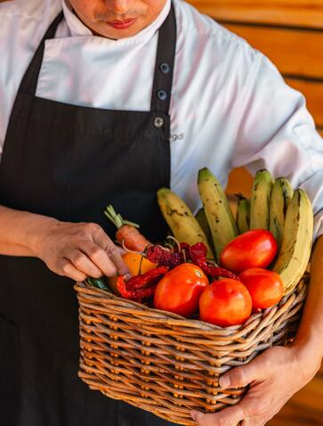 Chef holding wicker basket of fresh vegetables at Amankora's market excursion in Punakha.