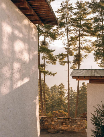 Amankora exterior in Thimphu, with white walls framing forested valley views.