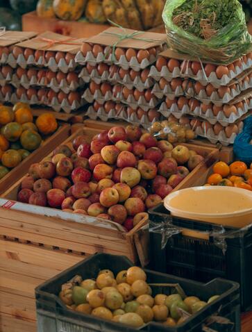 Colourful produce displayed at Thimphu farmers market near Amankora, including apples and squash in wooden crates.