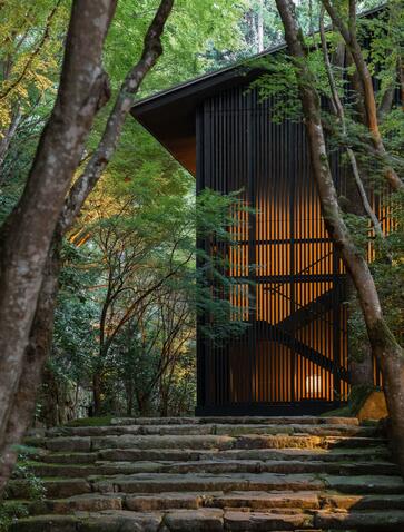 Modern wooden pavilion nestled amongst tall trees at Aman Kyoto resort, Japan.