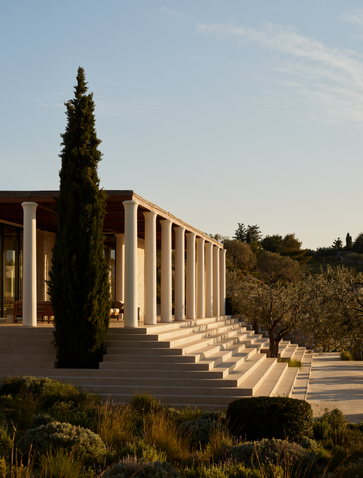 Villa outdoor area at Amanzoe resort in Greece, featuring columned architecture and cypress trees.
