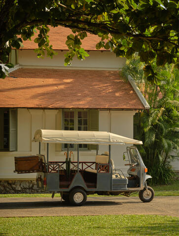 Vintage tuk-tuk parked on lawn at Amantaka, framed by climbing vines.