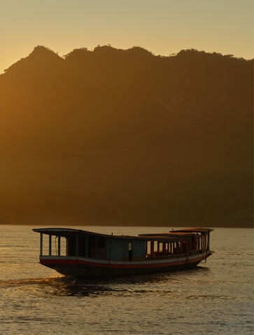 Traditional wooden boat on the Mekong River at sunset, Amantaka.