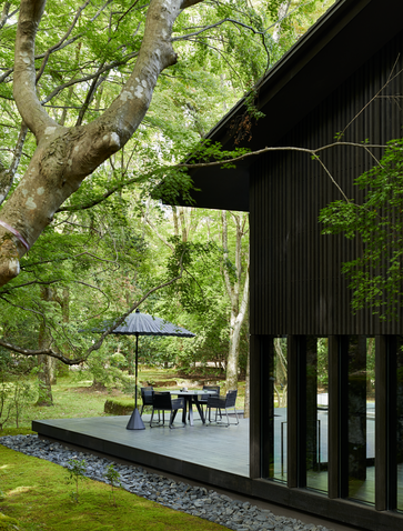 Exterior of The Living Pavilion at Aman Kyoto resort, with dark wooden structure and verdant garden surroundings.