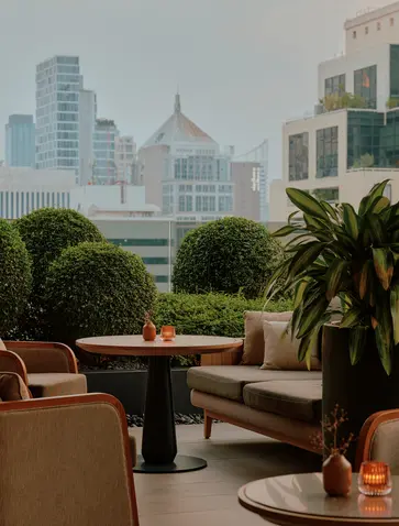 Aman Lounge seating area with city views of Bangkok's skyline and temples in the distance.