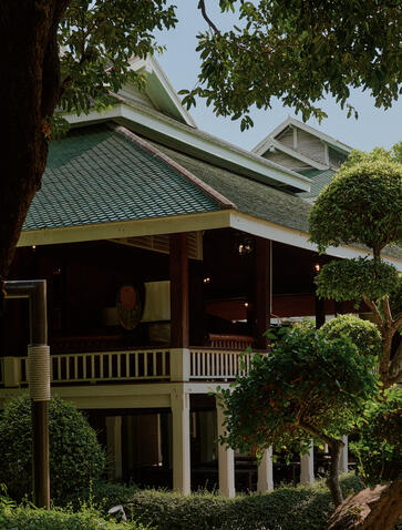 Nai Lert Heritage House exterior with traditional Thai architecture and pitched green roof, Aman Nai Lert Bangkok.