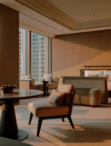 Spacious bedroom at Aman Nai Lert Bangkok with mid-century chair, bed, and floor-to-ceiling windows overlooking the city.