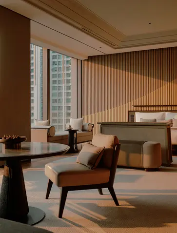 Spacious bedroom at Aman Nai Lert Bangkok with mid-century chair, bed, and floor-to-ceiling windows overlooking the city.