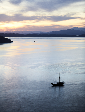 Traditional sailing boat on calm waters at Amandira, Indonesia, at dusk.