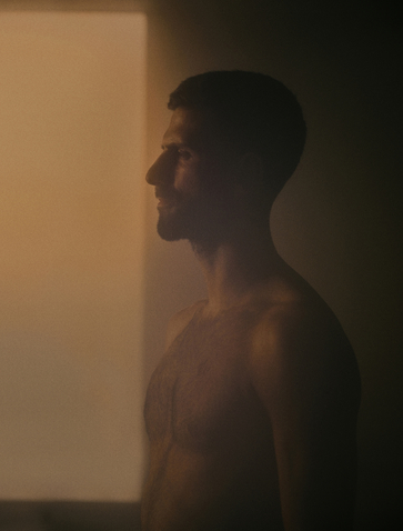 Novak Djokovic in profile, shirtless against warm, diffused light at Amanpuri.