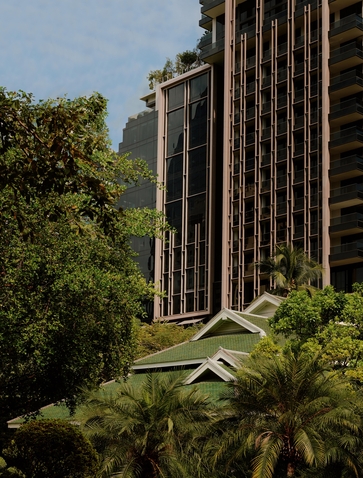 Exterior of Aman Nai Lert Bangkok with vertical timber detailing, framed by tropical greenery.