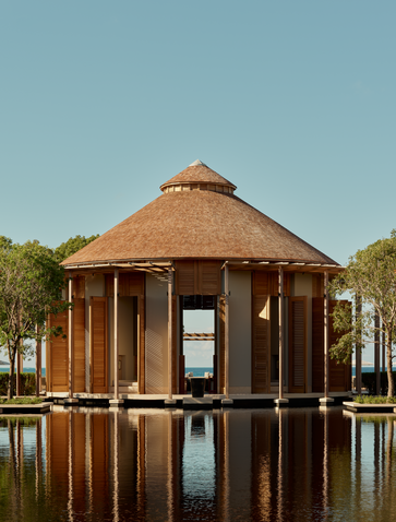 Amanyara's arrival pavilion with thatched roof reflected in still water, Turks and Caicos.