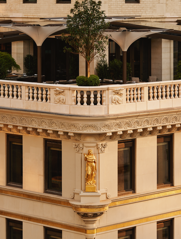 Exterior view of the Crown Building at Aman New York, featuring neoclassical architecture with ornate balconies and arched windows.
