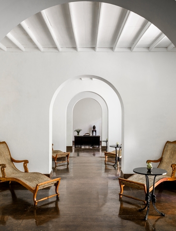 Spa corridor at Amangalla with arched ceiling, wooden chairs, and serene perspective down the passage.
