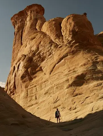 A climber ascending a via ferrata route on a towering sandstone formation at Amangiri, Utah.