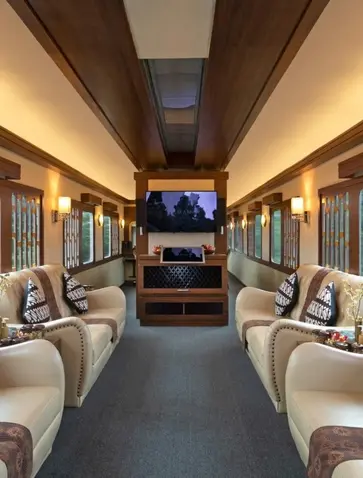 Amanjiwo resort's private train carriage interior with cream-coloured seats facing each other, warm lighting, and a screen at the centre.