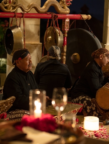 Candlelit Ramayana dinner setting at Amanjiwo resort, with guests seated at an elegantly dressed table overlooking Borobudur temple.