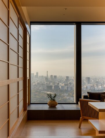 Deluxe room at Aman Tokyo overlooking the city skyline through floor-to-ceiling windows.