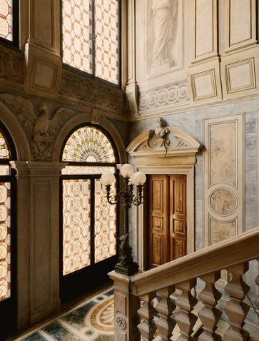 Stone staircase at Aman Venice with arched windows and ornate balustrade in Venice, Italy.