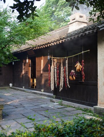 Amanfayun dining venue with dark timber façade and hanging lanterns, stone courtyard beyond.
