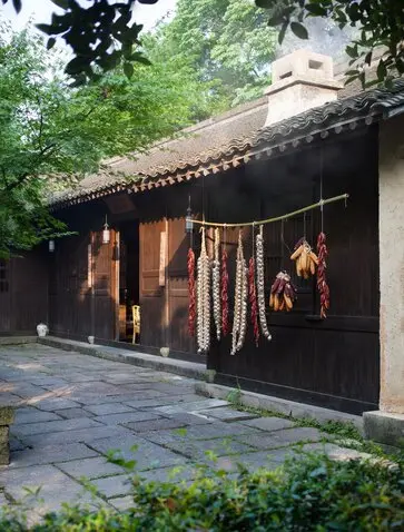 Amanfayun dining venue with dark timber façade and hanging lanterns, stone courtyard beyond.