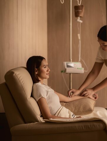 Wellness therapist administering IV drip treatment to guest at Aman Nai Lert Bangkok wellness clinic.