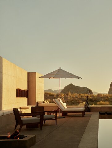 Amangiri suite with poolside seating and desert views at sunset, resort in USA.