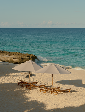 Amanyara's private beach with sandy shore, parasol, and turquoise waters in Turks and Caicos.
