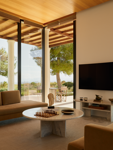Zona living di villa con finestre panoramiche che affacciano sul giardino ad Amanzoe resort, Grecia.