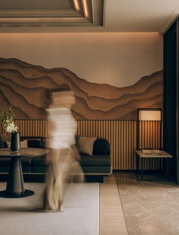 Terrace Suite at Aman Nai Lert Bangkok with curved wooden wall feature and contemporary furnishings.