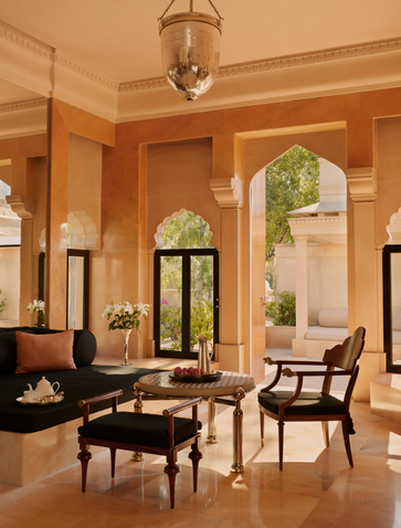 Terrace Haveli Suite living area at Amanbagh with warm ochre walls, traditional furnishings and arched doorway.