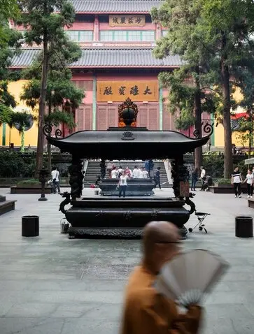 法云安缦度假村内，僧侣在庭院中行走，背景为灵隐寺古建筑。
