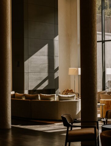 Winter garden at Aman Rosa Alpina with modernist seating and warm natural light filtering through tall windows.