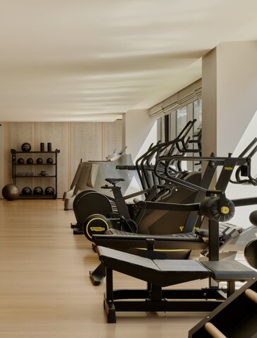 Fitness studio at Aman New York with exercise equipment and wooden flooring.