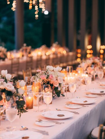 アマノイ リゾートのビーチクラブレストランで、キャンドルライトに照らされたウェディングレセプションのディナーテーブル。