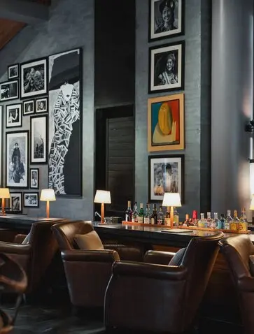 The Bar at Amanoi features a dark wall gallery with framed artworks, wooden bar seating, and warm candlelit ambiance.