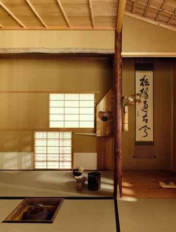 Serene tea house interior at Aman Kyoto resort with tatami mats, sliding paper screens and wooden beams.