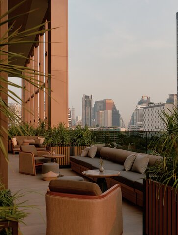 曼谷奈乐安缦酒店露台，配有座椅和城市天际线景观。