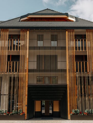 Entrance to Aman Rosa Alpina, a wooden-clad building with vertical timber detailing and dark ground-floor doors in Italy.