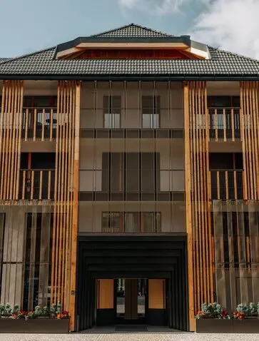 Entrance to Aman Rosa Alpina resort, featuring a wooden façade with vertical panelling and large glass doors.